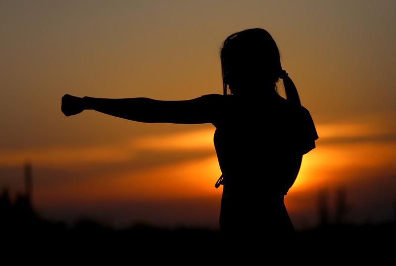 kobieta ćwiczy uderzenie pięścią gdy słońce zachodzi